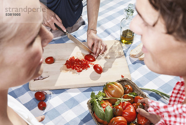 Italien  Toskana  Magliano  Junge Frau beim Tomatenschneiden mit Freunden im Vordergrund