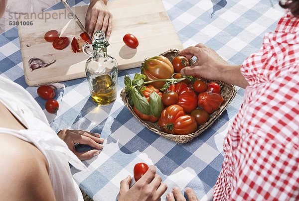 Italien  Toskana  Magliano  Junge Frau beim Tomatenschneiden mit Freunden im Vordergrund