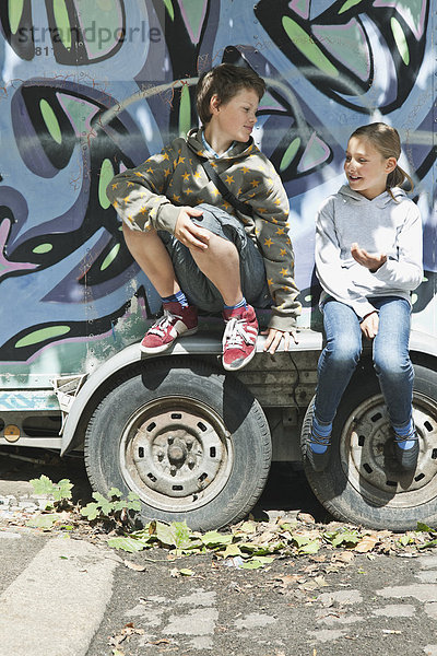 Junge und Mädchen sitzen auf einem Graffiti-Truck.