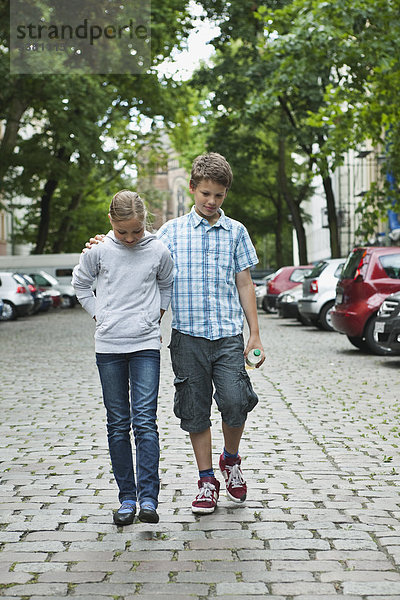 Junge und Mädchen gehen als Paar auf der Straße spazieren.