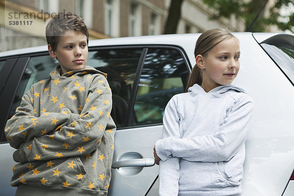 Junge und Mädchen  die sich auf das Auto stützen