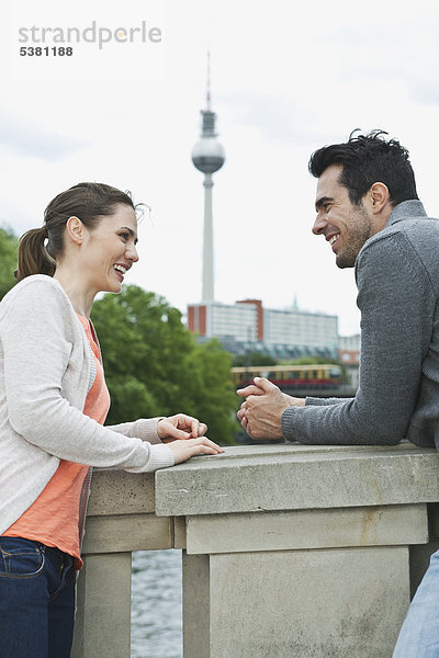 Deutschland  Berlin  Paar auf der Brücke stehend und sprechend