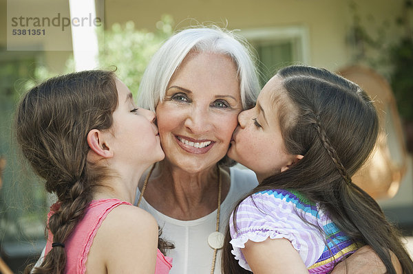Deutschland  Bayern  Enkelinnen küssen Großmutter  Nahaufnahme