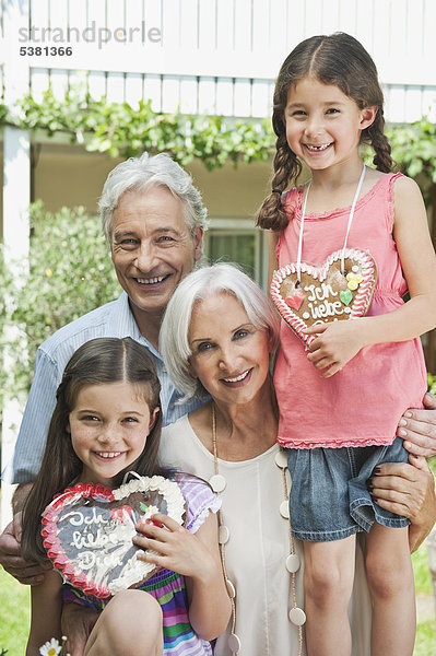 Deutschland  Bayern  Großeltern mit Enkelin mit Lebkuchen  lächelnd  Portrait