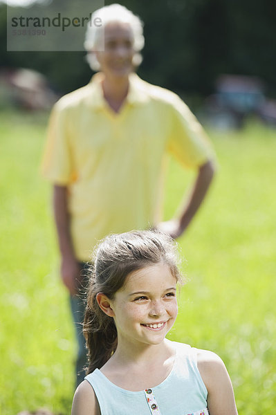 Mädchen lächelt mit Großvater im Hintergrund