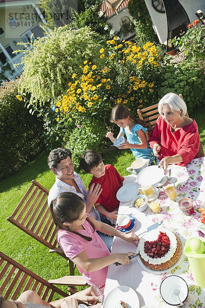 Deutschland  Bayern  Familie bei Kaffee und Kuchen im Garten  lachend