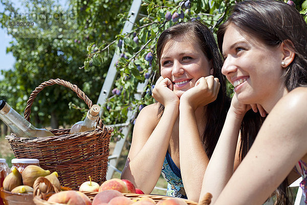 Lächelnde Frauen picknicken im Obstgarten