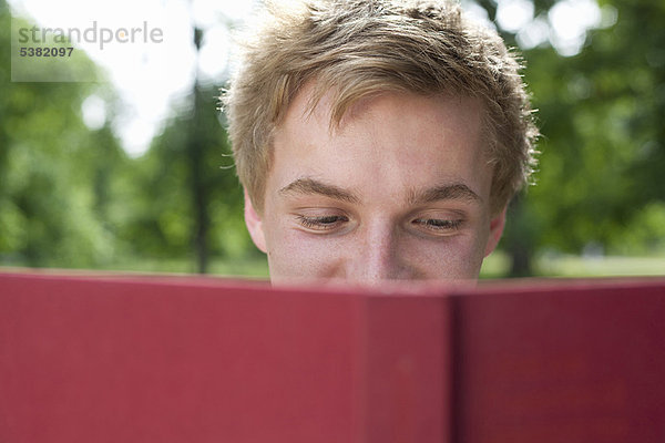 Teenager Junge liest im Park