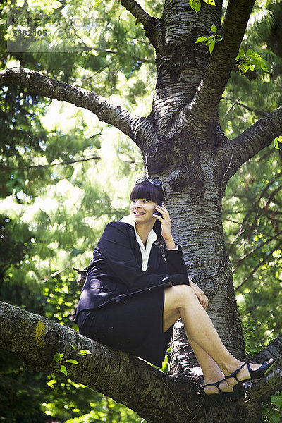 Geschäftsfrau am Handy im Baum