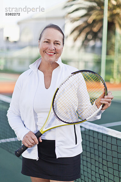 Ältere Frau mit Tennisschläger auf dem Platz