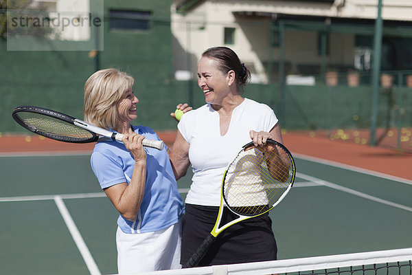 Ältere Frauen umarmen sich auf dem Tennisplatz
