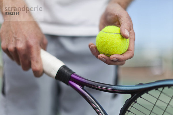 Älterer Mann mit Tennisball und Schläger