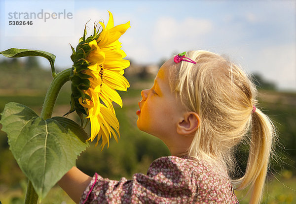 Mädchen riechende Sonnenblume im Freien