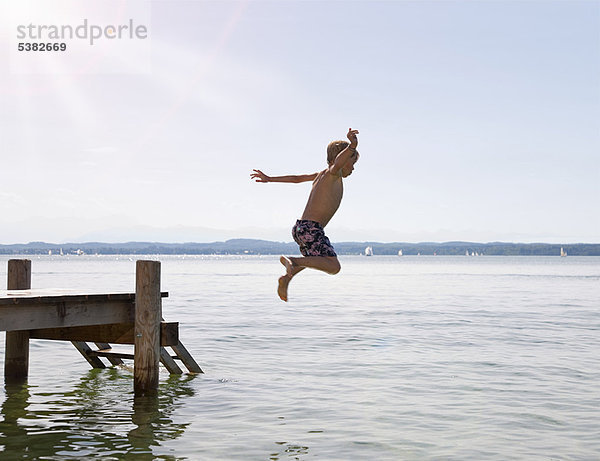 Junge  der vom Dock in den See springt.