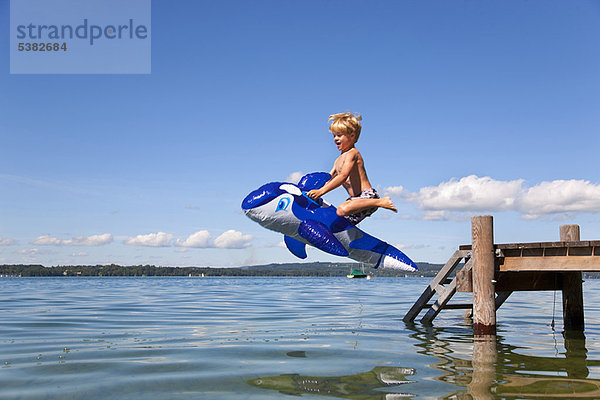 Junge springt in den See mit Spielzeugwal