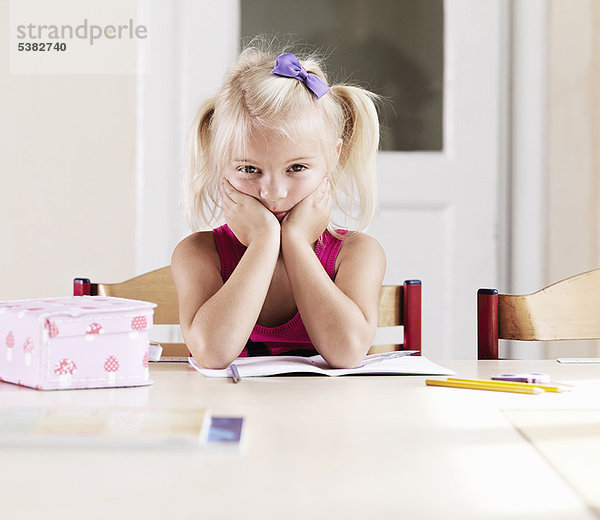 Gelangweiltes Mädchen bei den Hausaufgaben am Tisch