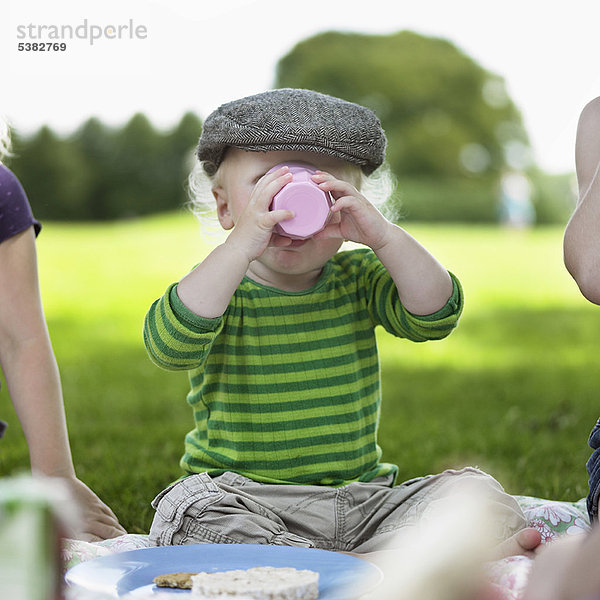 Junge trinkt aus Tasse beim Picknick