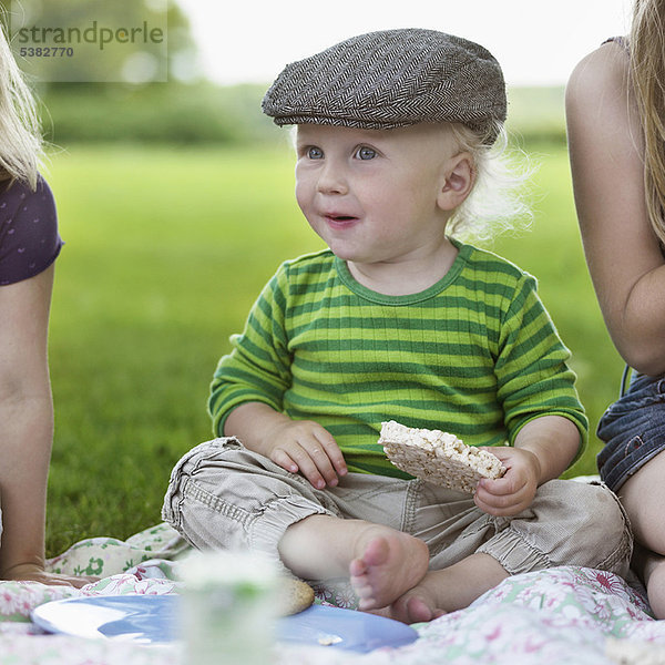 Junge isst Reiskuchen beim Picknick