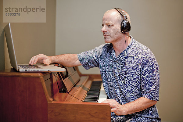 Mann spielt Musik mit Klavier und Laptop