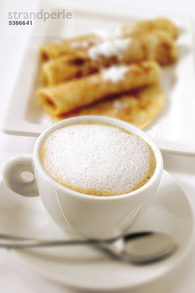 Eine Tasse Cappuccino  im Hintergrund unscharf Crepes