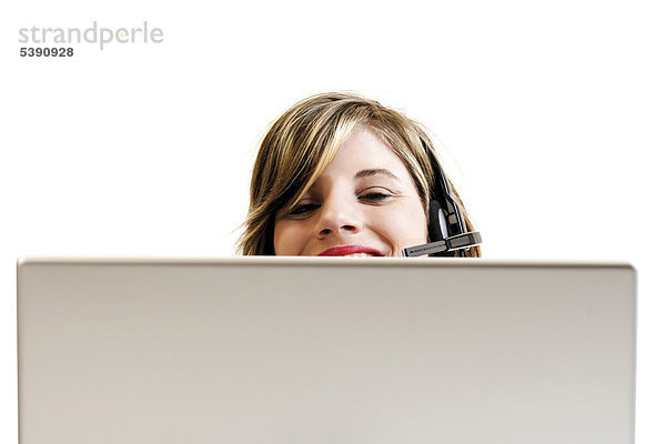 Junge Frau mit Headset hinter einem Laptop - Callcenter