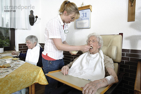 Im Altenheim  Pflegeheim  Pflegerin hilft einer Seniorin beim Essen