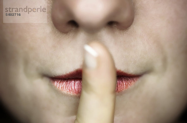 Frau hält Finger vor den Mund  Geste für Schweigen mund