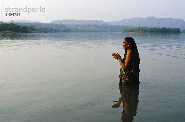 Eine Frau steht im kalten klaren Wasser des Flusses Ganges und betet zu Gott  Haridwar  Uttarakhand  früher Uttaranchal  Indien  Asien