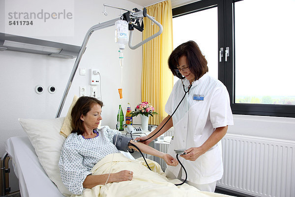 Krankenschwester misst den Blutdruck einer Patientin im Krankenbett  Krankenhaus