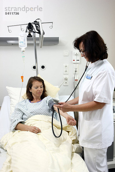 Krankenschwester misst den Blutdruck einer Patientin im Krankenbett  Krankenhaus