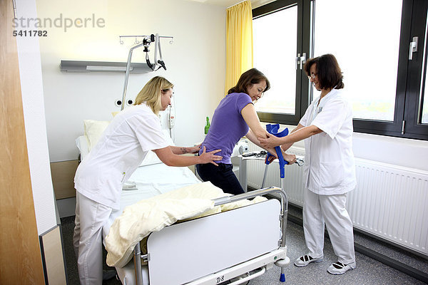 Krankenschwestern helfen Patientin bei Gehversuchen an Gehhilfen  Mobilisierung nach einer Operation  Krankenhaus