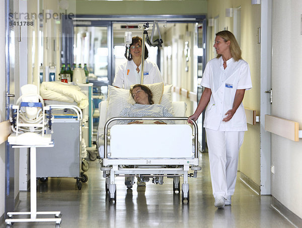 Krankenschwestern transportieren eine Patientin mit dem Bett innerhalb der Krankenstation  Krankenhaus