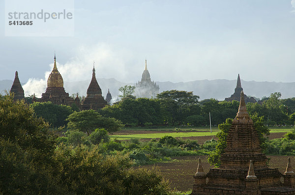 Aufsteigender Rauch  Nebel und Abendlicht zwischen den Feldern  Tempel und Pagoden  Bagan  Myanmar  Burma  Birma  Südostasien  Asien