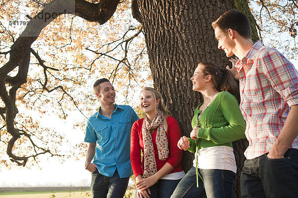 Junge Leute stehen an einem Baum