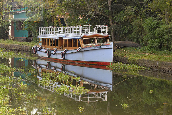 Ein Boot spiegelt sich in den Backwaters nahe Kumarakom  Kerala  Indien  Asien