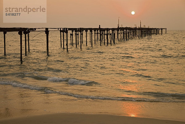 Sonnenuntergang über dem Arabischen Meer hinter der Ruine des Piers von Alleppey  Kerala  Indien  Asien