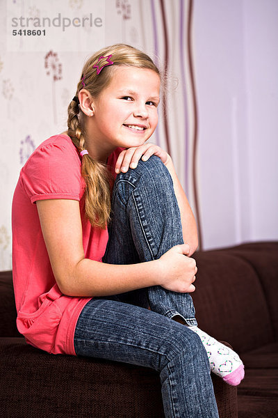 11-jähriges Mädchen sitzt auf Sofa