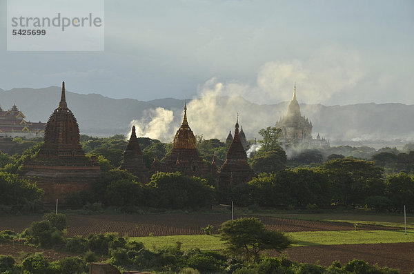 Auftsteigender Rauch und Abendlicht zwischen den Feldern  Tempel und Pagoden  Bagan  Myanmar  Burma  Birma  Südostasien  Asien