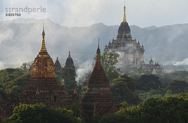 Auftsteigender Rauch und Abendlicht zwischen den Feldern  Tempel und Pagoden  Bagan  Myanmar  Burma  Birma  Südostasien  Asien