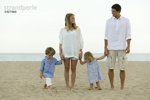 Familie hält sich am Strand an den Händen