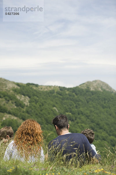 Eltern und Kinder auf der Wiese mit Blick auf die Berge  Rückansicht