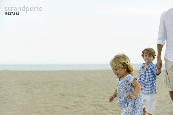 Kleines Mädchen hat Spaß am Strand mit der Familie