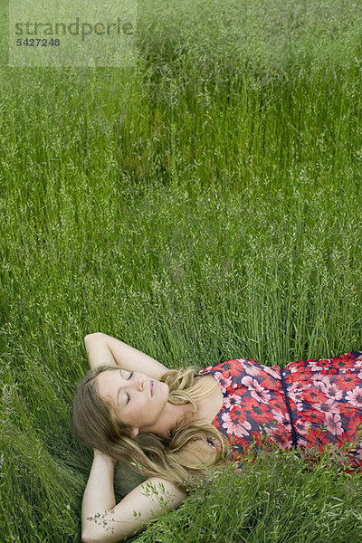 Junge Frau schlafend im hohen Gras