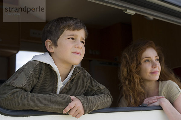 Junge und Mutter schauen aus dem Fenster des Wohnmobils.