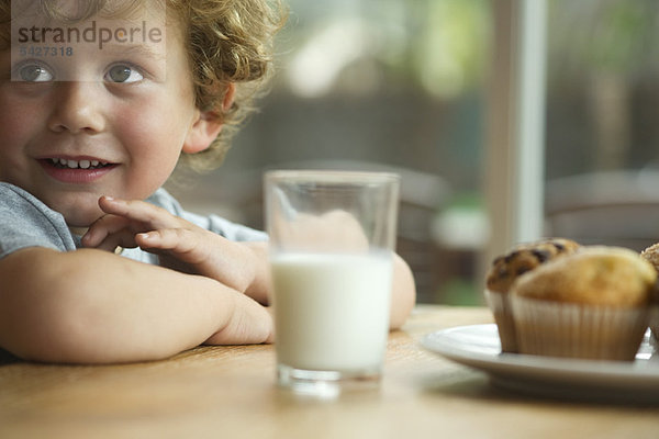 Kleiner Junge am Tisch sitzend mit Snack