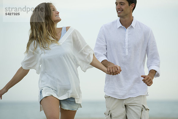 Paar geht Hand in Hand am Strand spazieren