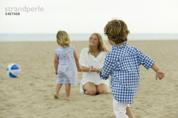 Junge spielt am Strand  Familie im Hintergrund