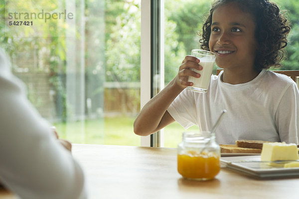 Mädchen trinken ein Glas Milch beim Frühstück