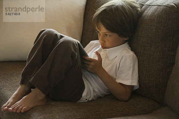 Junge entspannt auf Sofa mit digitalem Tablett