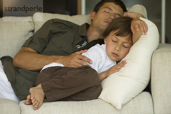 Vater und Sohn schlafen zusammen auf dem Sofa.